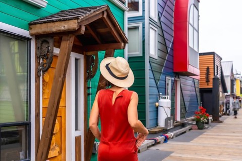 Female tourist wearing a straw hat and a red dress is enjoying a summer day walking down the