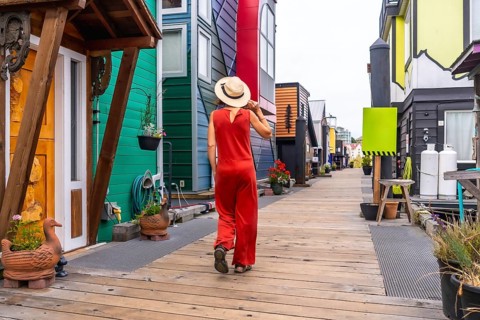 Tourist wearing a straw hat and a red jumpsuit is walking on a wooden walkway exploring the