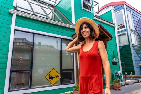 Happy tourist adjusting her straw hat while walking and smiling in front of colorful floating