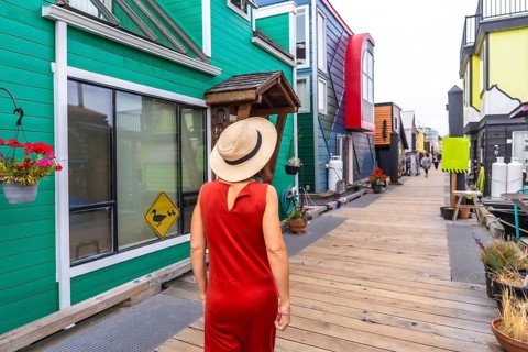 Tourist wearing a straw hat and orange dress walking along a wooden walkway, visiting vibrant