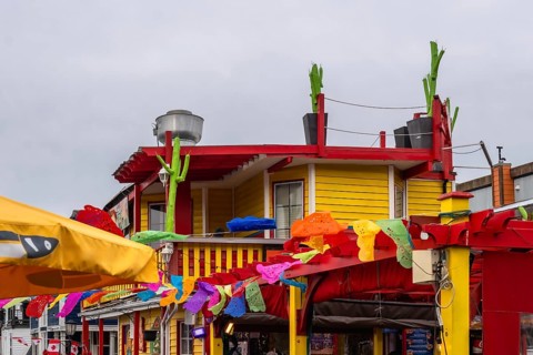 Vibrant mexican restaurant decorated with colorful papel picado and cacti, celebrating summer in