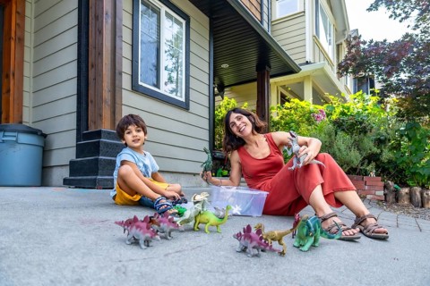 Mother and son sitting on the ground in their front yard, enjoying a sunny summer day while playing