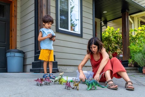 Mother and son enjoying quality time together, playing with dinosaur toys on the porch of their