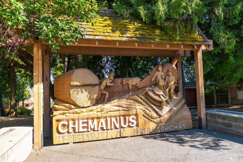 Wooden sculpture depicting loggers working with logs and tools, commemorating the rich history of