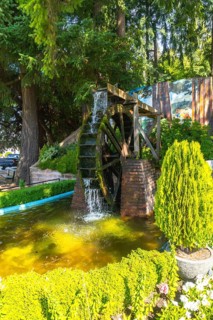 Water cascading over a moss covered water wheel in a vibrant garden within chemainus, british