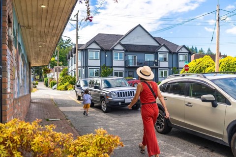 Tourists are walking along a street with parked cars in chemainus, a town known for its outdoor