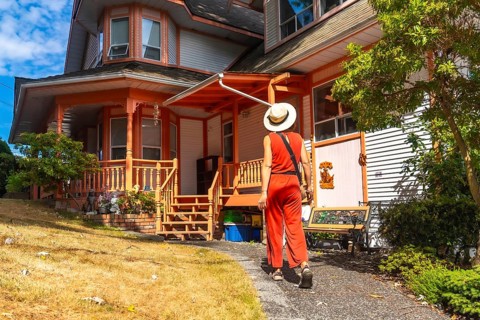 Tourist wearing a straw hat and orange jumpsuit walking along a gravel path beside a vibrant wooden
