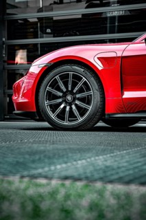 Side view of the front wheel of a red Porsche, focus on rim and body, Porsche Taycan, Deer