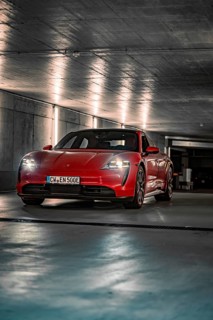Red Porsche Taycan parked in an illuminated underground car park with an urban atmosphere, Porsche