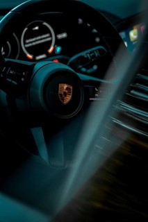 Close-up of a modern steering wheel with speedometer and LED indicators in a car, Porsche Taycan,