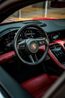 Modern car interior with red and black interior, showing steering wheel and instruments, Porsche