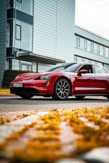 Modern red sports car in front of an office building on the street in daylight, Porsche Taycan,