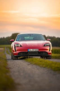 Front view of a red sports car on a gravel path at sunset, Porsche Taycan, deer car sharing. Calw,