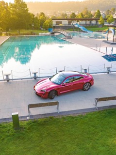 Red car parked next to swimming pool in urban area, Porsche Taycan, deer car sharing. Calw, Germany