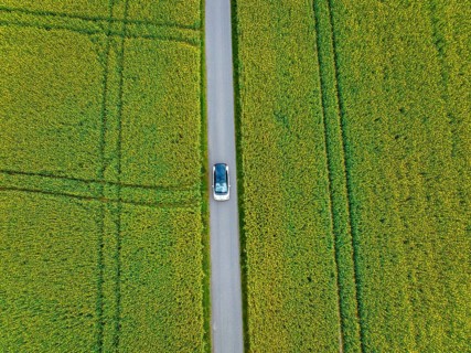 Aerial view of a car on a road between large fields, ID3 VW, deer car sharing. Calw, Germany