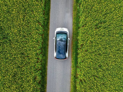 Aerial view of a car on a narrow road surrounded by green fields, ID3 VW, deer car sharing. Calw,