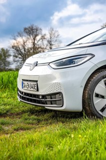 Side view of a wet car on a green field under cloudy sky, ID3 VW, deer car sharing. Calw, Germany