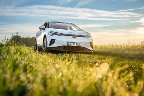 White car in a meadow at sunrise, peaceful natural environment, VW ID4 electric car, deer car