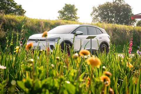 White car in front of flower field on a sunny day, nature and vehicle in harmony, VW ID4 electric