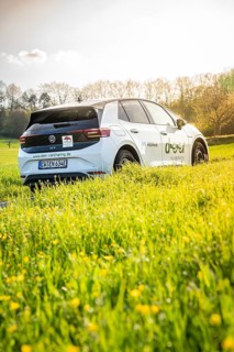 White car on green field in sunshine surrounded by nature, VW ID4 electric car, Deer Carsharing,