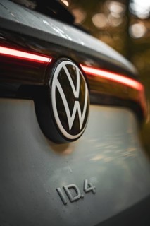 VW logo with rear light of a car in warm light in the forest, VW ID4 electric car, Deer Carsharing,