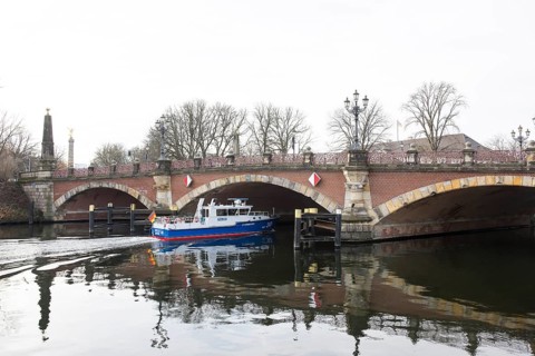 A water protection police ship sails under the Luther Bridge near Bellevue Palace on the Spree in