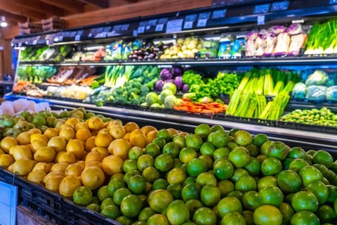 Fresh limes and lemons are piled high in the foreground, with a colorful display of various fruits