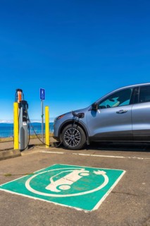 Modern electric car charging at a seaside station on a bright sunny day, highlighting the