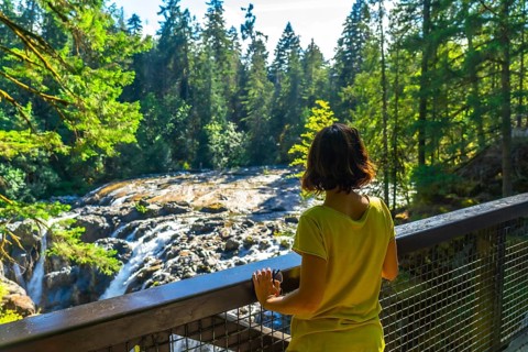 Female tourist admiring englishman river falls in vancouver island, british columbia, canada,