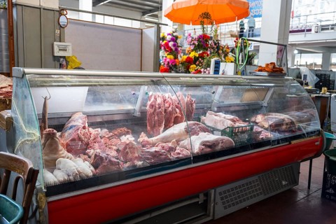 Refrigerated display cabinet with a selection of different types of meat in a butcher shop,