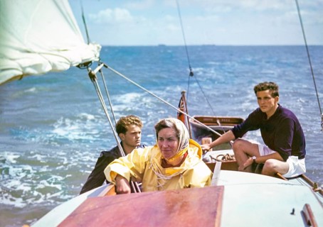 Woman sailing on small yacht with two young men, UK 1950s
