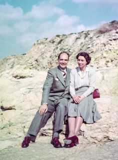 Portrait of smartly dressed man and woman, couple sitting on rocks at the seaside c 1956