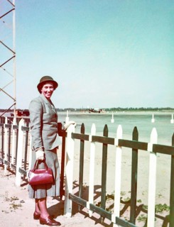 Portrait of smartly dressed woman wearing a suit and hat standing at an airport c 1956
