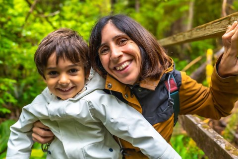 Mother and son are enjoying a hike in a lush rainforest, sharing a happy moment together surrounded