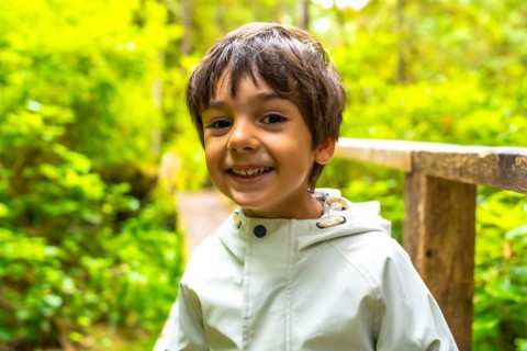 Young child smiles while exploring a lush rainforest trail in ucluelet, a town on vancouver island,