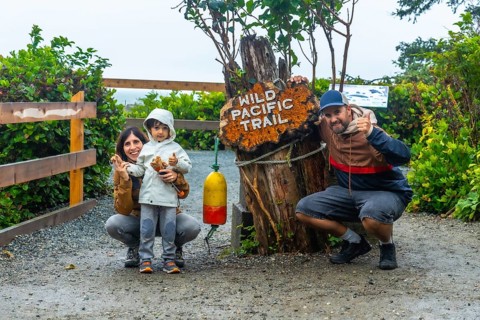 Happy family posing for a photo at the entrance of the wild pacific trail in ucluelet, british