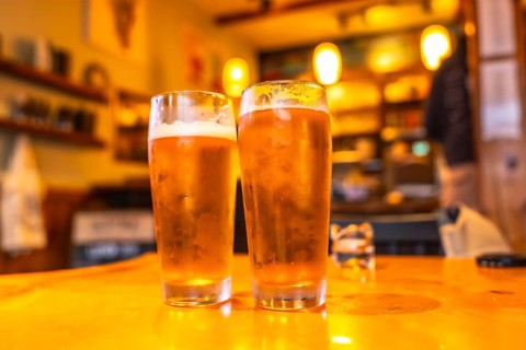 Two glasses of cold craft beer sit on a wooden table in a cozy pub in ucluelet, british columbia,