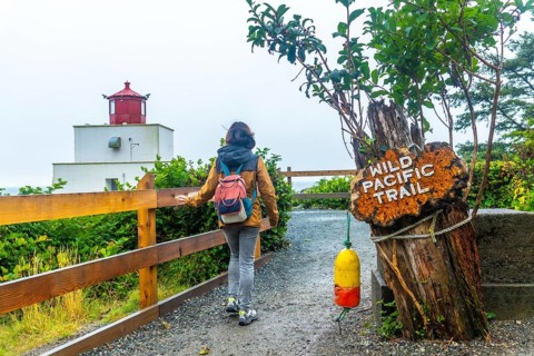Female tourist walking towards amphitrite point lighthouse on the wild pacific trail near ucluelet