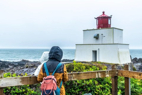 Two tourists in raincoats and backpacks enjoying the misty view of amphitrite point lighthouse,