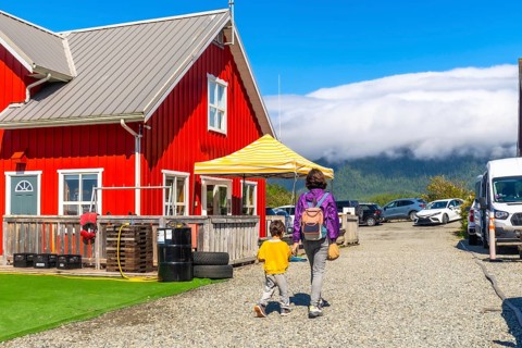 Mother and her young child are walking away from a vibrant red building in tofino, vancouver