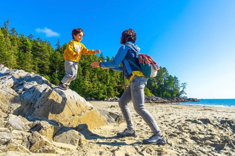 On a sunny summer day in tofino, british columbia, a mother extends her hands to help her child