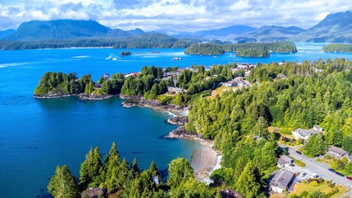 Aerial view capturing tofino on vancouver island, showcasing lush green forests, blue ocean waters,