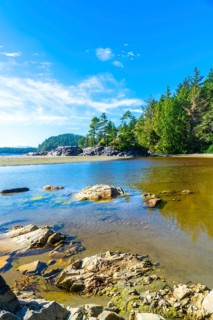 Crystal clear shallow inlet water reflects the vibrant summer sky, creating a picturesque scene in