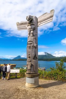 Wooden totem pole standing on a base overlooking the harbor in tofino, british columbia, canada,