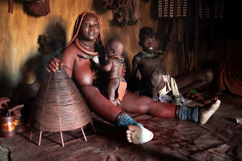 Himba woman sitting with baby, Himba perfume, scented smoke from burning plants, Himba village,