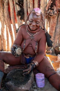 Himba woman grinding grain on a stone, Himba village, Kaokoveld, Kunene, Namibia