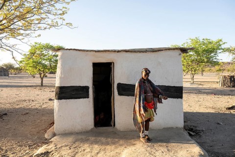 Woman in front of hut, village in the savanna, Hakaona tribe, also Havakona or Hakawona, near