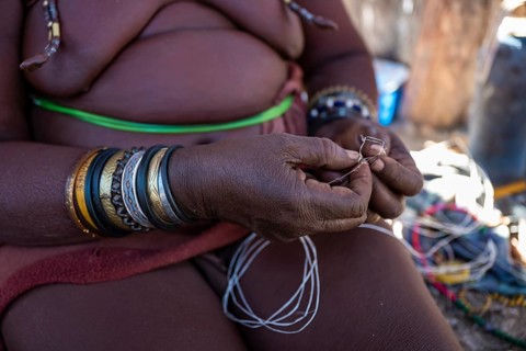 Himba woman doing handiwork, making hand bands for tourists, traditional Himba village, Kaokoveld,