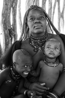 Black and white, Himba woman with baby and grinning child, traditional Himba village, Kaokoveld,