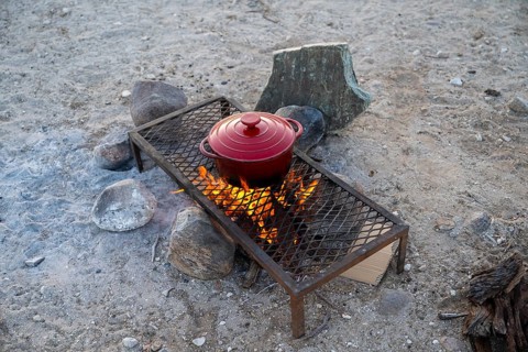 Single pot cooks on a campfire, preparing food while camping